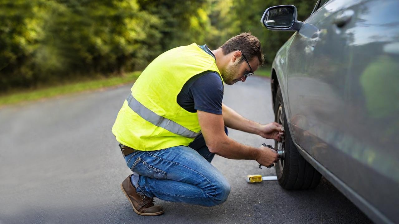 man fixing car wearing a safety vest